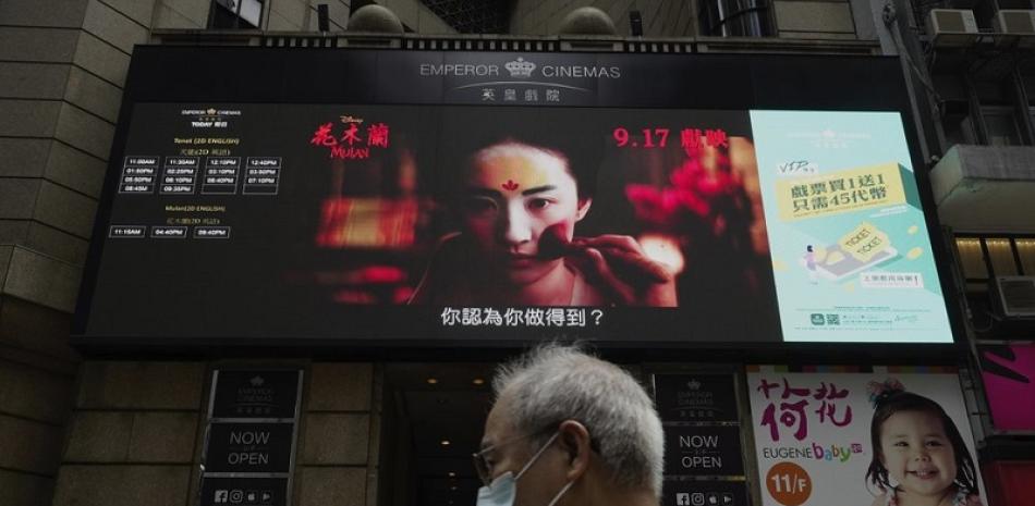 Gente pasa junto a una enorme pantalla que anuncia la película de Disney "Mulan" en una calle del centro de Hong Kong, China. Foto: AP/Vincent Yu.
