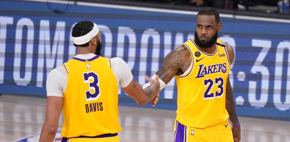 Anthony Davis (3) y LeBron James (23) de Los Angeles Lakers se dan la mano en los momentos finales de su victoria por 114-108 sobre los Nuggets de Denver en un juego de baloncesto de la postemporada de la conferencia de la NBA este jueves, en Lake Buena Vista, Florida.