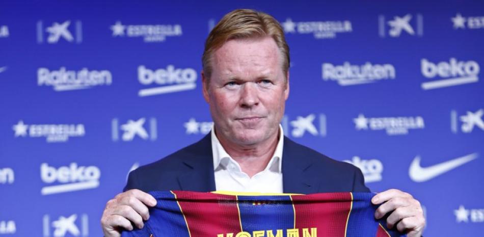 Ronald Koeman muestra la camiseta con su nombre durante su presentación oficial como nuevo técnico de Barcelona. El técnico dejó a los veteranos Luis Suárez y Arturo Vidal fuera del equipo que venció al club de tercera división Gimnástic de Tarragona 3-1 en un amistoso el sábado, 12 de septiembre,.