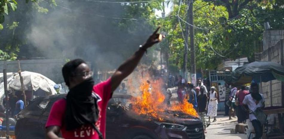 Un manifestante sostiene una caja de fósforos tras prender fuego a un auto gubernamental durante una protesta reclamando justicia por un estudiante que murió por disparos de la policía una semana antes en una universidad durante una movilización por los puestos gubernamentales de profesor, en Puerto Príncipe, Haití, el 5 de octubre de 2020. (AP Foto/Dieu Nalio Chery)