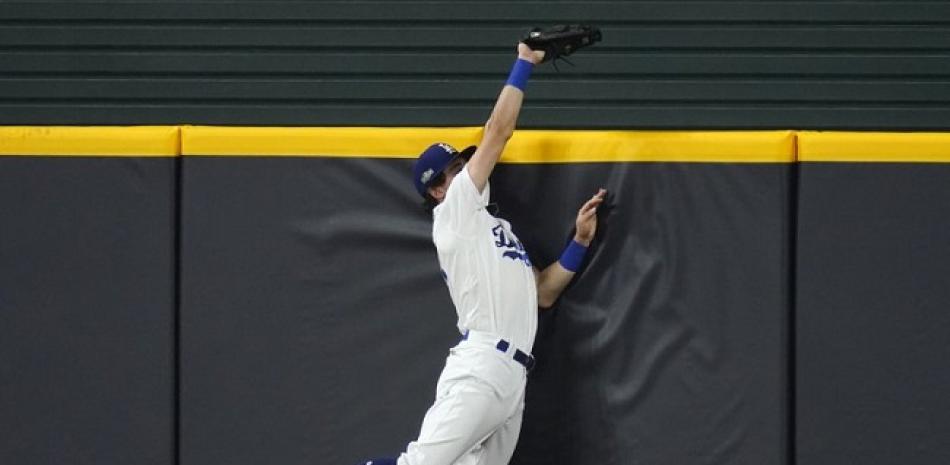 El jugador de los Dodgers de Los Ángeles Cody Bellinger salta contra el muro y atrapa una pelota para evitar un jonrón del jugador de los Padres de San Diego Fernando Tatís Jr., en el séptimo inning. (AP Foto/Sue Ogrocki)