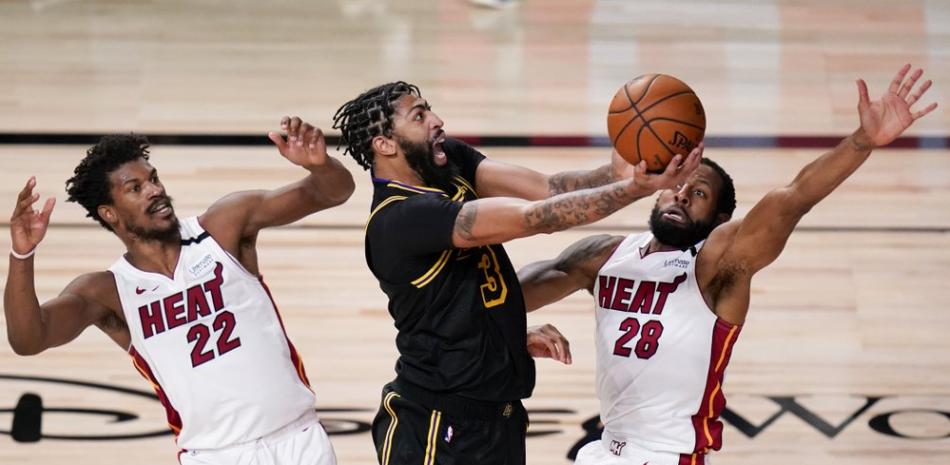 El alero de Los Angeles Lakers Anthony Davis dispara entre el alero de los Miami Heat Jimmy Butler, a la izquierda, y el base Andre Iguodala durante la segunda mitad del Juego 5 de las Finales de la NBA este viernes.