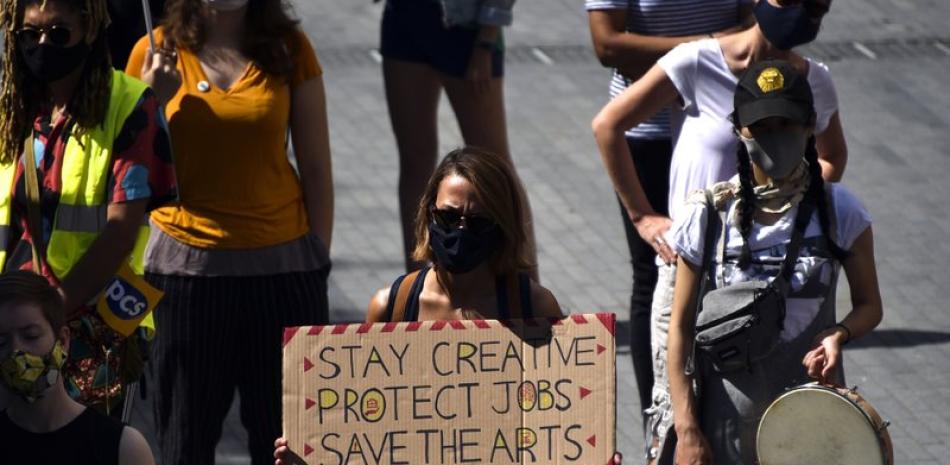 En esta foto del 1 de agosto de 2020, trabajadores del teatro protestan afuera del Teatro Nacional contra contra los despidos masivos de empleos mal pagados en las artes debido a la pandemia del coronavirus, en Londres. El gobierno británico anunció el lunes 12 de octubre dádivas de 257 millones de libras esterlinas para ayudar a casi 1.400 organizaciones culturales y de artes a sobrevivir la pandemia. (AP Foto/Alberto Pezzali, Archivo)