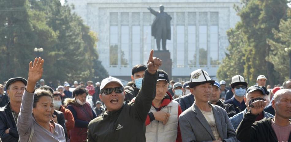 Manifestantes reaccionan tras escuchar a un orador durante una protesta ante un edificio gubernamental, con una estatua de Vladimir Lenin de fondo, en Biskek, Kirguistán, el 14 de octubre de 2020. (AP Foto/Vladimir Voronin)