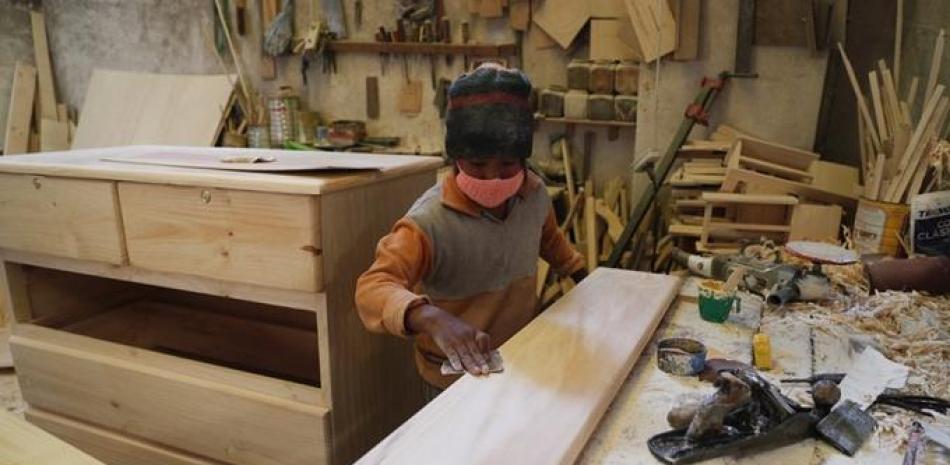 Yuri Delgado lija madera en el taller de carpintería de su familia en El Alto, Bolivia. El niño de 11 años estudia cada mañana antes de trabajar en el taller, después de que el año escolar fue cancelado en su país debido a la pandemia del nuevo coronavirus. Foto: AP/Juan Karita.