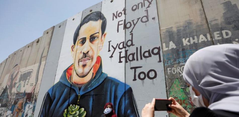 Una mujer palestina se toma fotos frente a un mural que representa a Iyad al-Halaq, el palestino desarmado y autista que fue asesinado a tiros por la policía israelí, en Belén, en Cisjordania ocupada por Israel