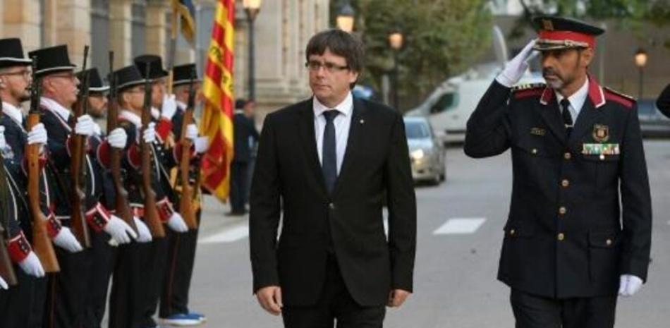 El entonces presidente catalán, Carles Puigdemont, pasa revista a unos agentes de los Mossos d'Esquadra junto al entonces jefe de la policía regional, Josep Lluís Trapero, el 10 de septiembre de 2017 en Barcelona. / AFP