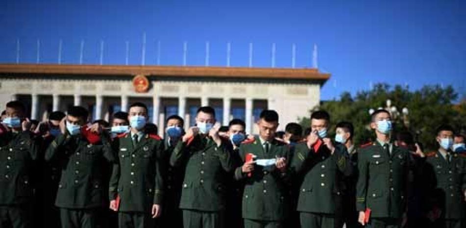 Los policías paramilitares chinos se quitan las máscaras mientras se reúnen en la Plaza de Tiananmen de Beijing frente al Gran Salón del Pueblo antes de una ceremonia que marca el 70 aniversario de la entrada de China en la Guerra de Corea, el 23 de octubre de 2020. NOEL CELIS / AFP