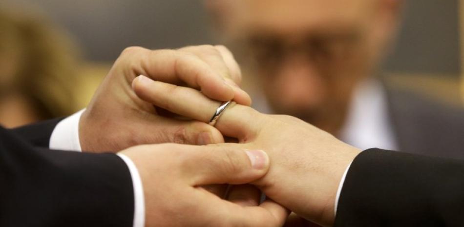 En esta foto de archivo del 21 de mayo de 2015, Mauro Cioffari, izquierda, coloca el anillo de bodas en el dedo de su pareja Davide Conti al registrar su unión civil en Roma. (AP Foto/Gregorio Borgia, archivo)