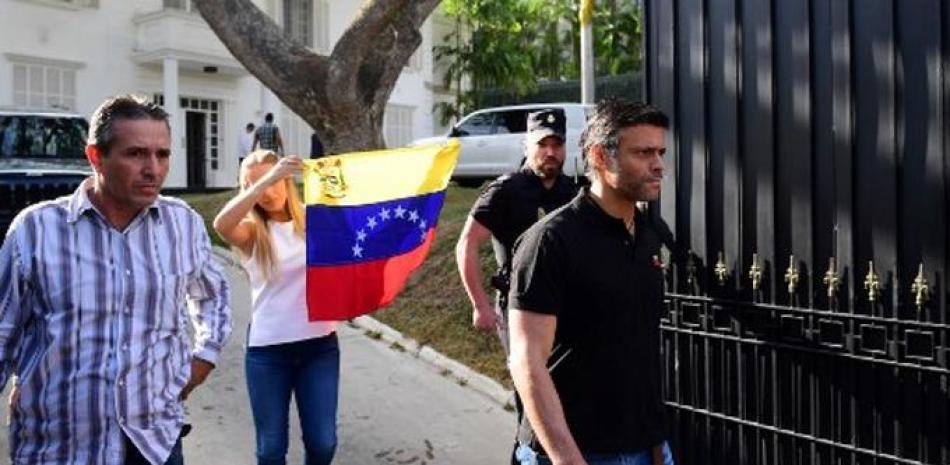 En esta imagen de archivo tomada el 2 de mayo de 2019, el destacado político opositor venezolano Leopoldo López (derecha) seguido de su esposa Lilian Tintori (c) con una bandera venezolana, sale de la embajada española en Caracas. Foto: Ronaldo Schemidt/AFP.