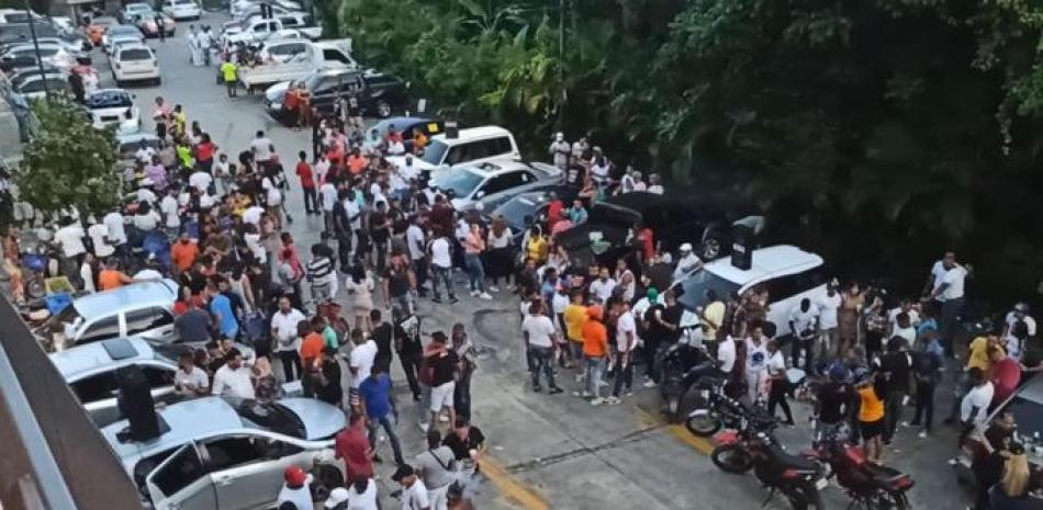 Decenas de personas concentradas en el parqueo de una plaza del kilómetro 18 de la Autopista Duarte sin medidas de seguridad para evitar la propagación del coronavirus.