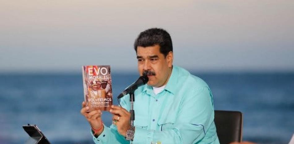 Nicolas Maduro sosteniendo un libro de Evo Morales. / AFP
