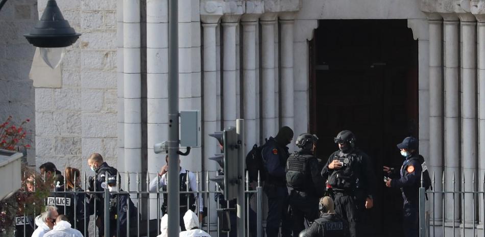 Miembros franceses de la unidad de policía táctica de élite RAID ingresan para registrar la Basílica de Notre-Dame de Nice mientras los agentes forenses esperan afuera después de un ataque con cuchillo en Niza el 29 de octubre de 2020. Valery Hache / AFP