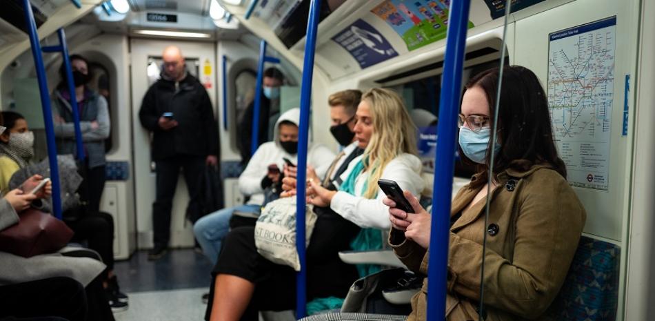 Los viajeros, la mayoría con máscaras debido a la pandemia del coronavirus, viajan en un tren subterráneo de Londres. Foto vía Tolga Akmen / AFP
