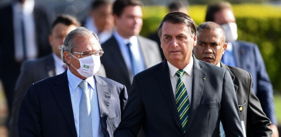 El presidente brasileño, Jair Bolsonaro (derecha) y su ministro de Finanzas, Paulo Guedes, asisten a la ceremonia de izamiento de la bandera nacional antes de una reunión ministerial en el Palacio de la Alvorada en Brasilia. Evaristo Sa / AFP