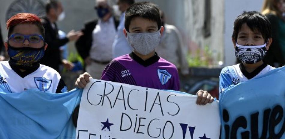 Niños sostienen un cartel deseando un feliz cumpleaños a la ex estrella del fútbol argentino Diego Maradona, actual entrenador del equipo de fútbol Gimnasia y Esgrima La Plata. Foto vía Juan Mabromata / AFP