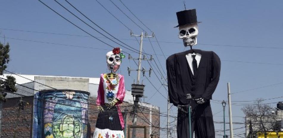 Figuras gigantes de calaveras hechas de cartón en el barrio de Santa Cecilia, previo al Día de Muertos en la Ciudad de México, en medio de la pandemia de COVID-19. Foto vía Alfredo Estrella / AFP