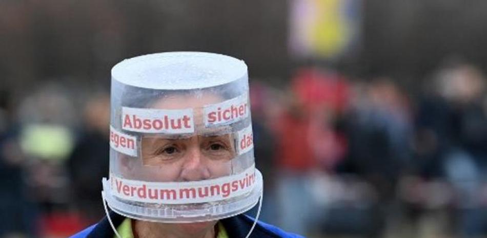 Un participante usa un balde como protección durante una manifestación contra las restricciones del coronavirus Covid-19 en Munich, sur de Alemania. Foto vía Christof Stache / AFP.
