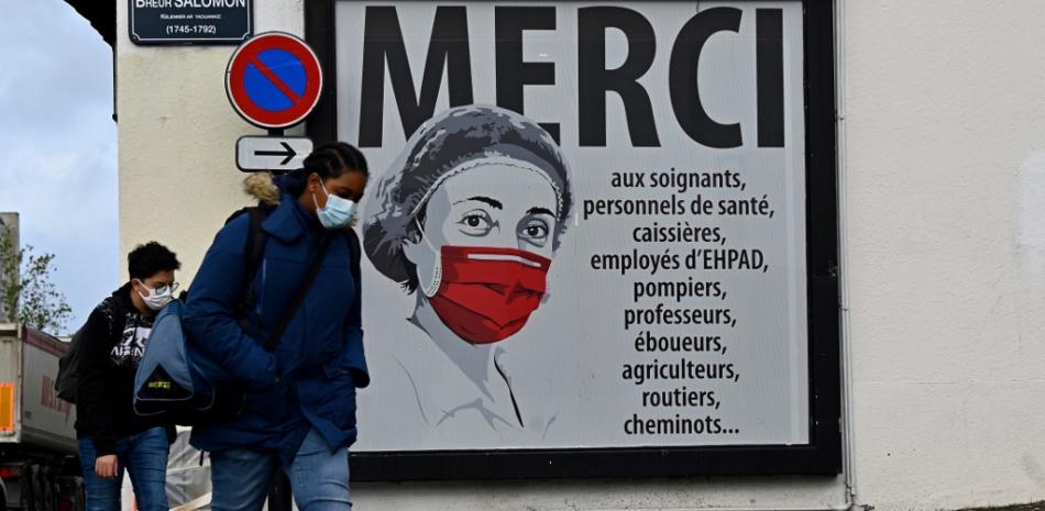 La gente pasa junto a un cartel que muestra a una enfermera con una máscara protectora y agradece a todas las profesiones que han apoyado la pandemia del coronavirus COVID-19 en una calle de Rennes, en el oeste de Francia. Damien Meyer / AFP