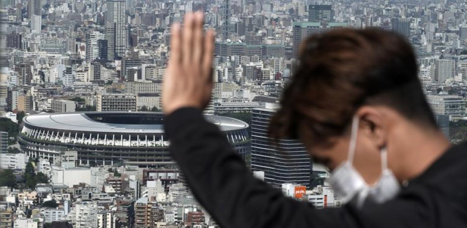 Un ciudadano japones, con mascarilla, se deleita desde un observatorio con el Estadio Nacional, sede de los Juegos Olímpicos de Tokio, al fondo. (AP Foto/Eugene Hoshiko)