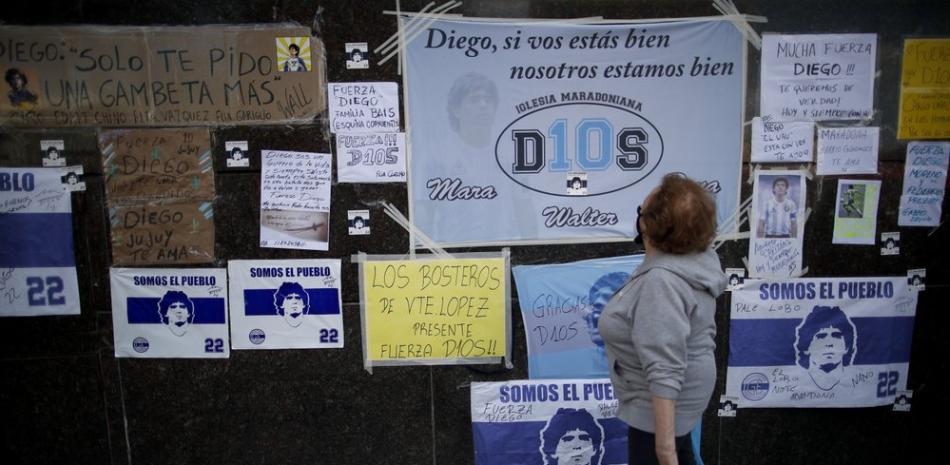 Una mujer observa un muro con mensajes de aliento a Diego Maradona en las afueras de la Clínica Olivos de Buenos Aires, donde la leyenda del fútbol mundial fue operado, este miércoles.