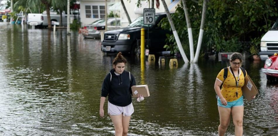 Victoria Rodriguez, a la izquierda, y Angela Mojica, caminan sobre una calle inundada en el parque de casas rodantes de Diftwood Acres, tras el paso de la tormenta tropical Eta, el martes 10 de noviembre de 2020, en Davie, Florida. (AP Foto/Lynne Sladky)