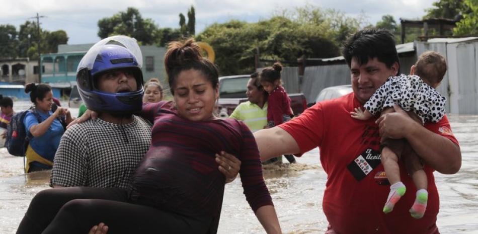 Una mujer embarazada es evacuada en brazos de una zona inundada por el huracán Eta en Honduras, el jueves 5 de noviembre de 2020. (AP Foto/Delmer Martinez)