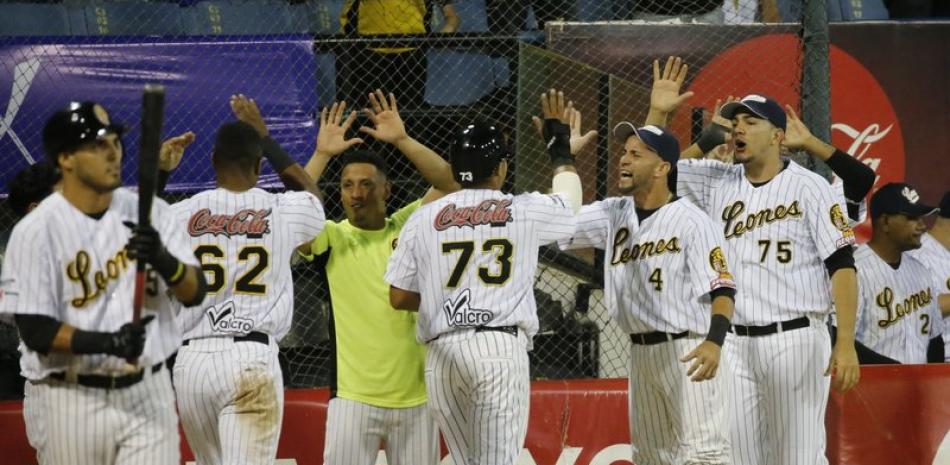 En esta foto del 5 de noviembre de 2019, los jugadores de los Leones del Caracas celebran tras anotar una carrera ante los Tigres of Aragua durante un juego de la liga de béisbol profesional, en Caracas.