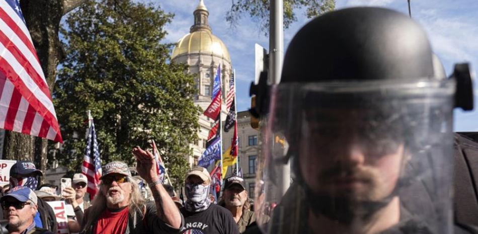 Agentes antidisturbios se colocan entre seguidores y opositores del mandatario Donald Trump, durante manifestaciones en Georgia, el sábado pasado. AP