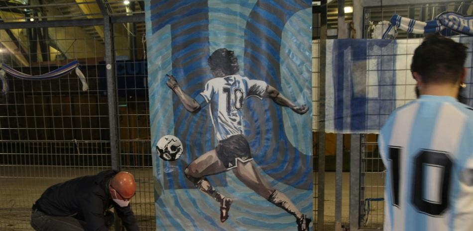 La gente presenta sus respetos en la entrada principal del estadio San Paolo en Nápoles frente a una imagen de la leyenda del fútbol argentino Diego Maradona. La leyenda del fútbol argentino murió a la edad de 60 años, anunció su portavoz. Carlo Hermann / AFP