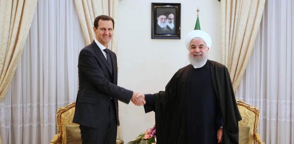 Esta fotografía de archivo publicada por la oficina del presidente iraní el 25 de febrero de 2019 muestra al presidente de Siria, Bashar al-Assad (izq.), Estrechando la mano de su homólogo iraní Hassan Rouhani en Teherán. Presidencia iraní / AFP