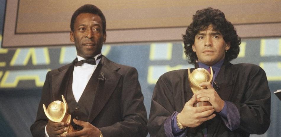 En esta foto de archivo de marzo de 1987, Pelé, izquierda, y Diego Maradona, sostienen trofeos durante una ceremonia de premiación en Italia. El gran futbolista argentino que estuvo entre los mejores jugadores de la historia y que llevó a su país al título de la Copa del Mundo de 1986 antes de luchar más tarde contra el consumo de cocaína y la obesidad, murió de un ataque cardíaco el miércoles 25 de noviembre de 2020 en su casa en Buenos Aires. Aires. Tenía 60 años.