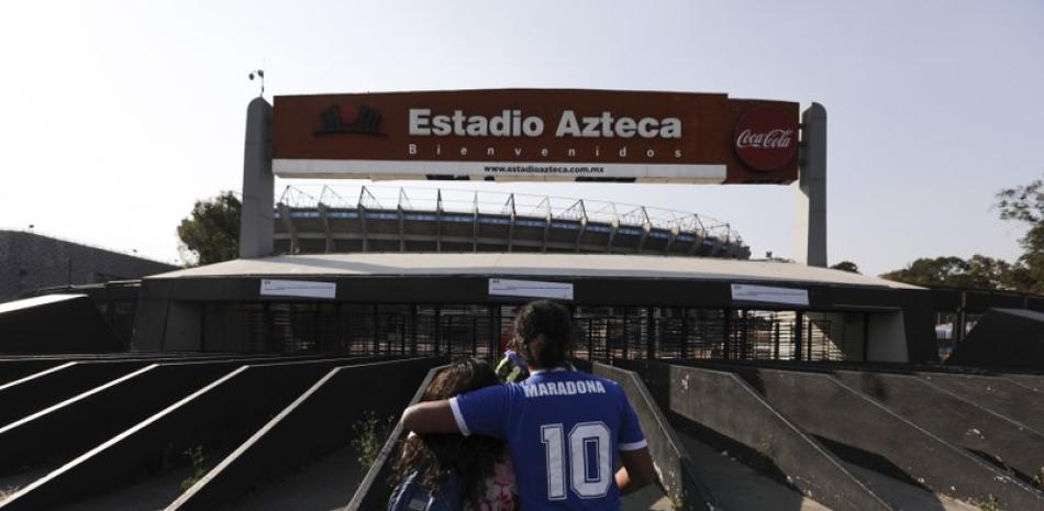 Una pareja, incluido un hombre con una camiseta que lleva el número 10 de Diego Maradona, se abraza frente al estadio Azteca de la Ciudad de México el miércoles 25 de noviembre de 2020 (AP Foto/Eduardo Verdugo)