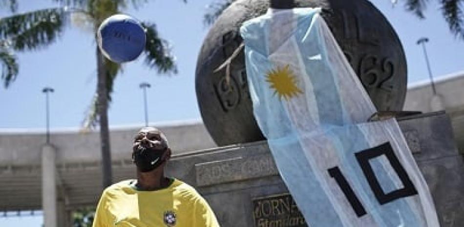 Marcio Pereira, de 57 años y quien se hace apodar "Pelé", domina el balón junto a un monumento adornado con una bandera argentina y con el 10 de Diego Maradon. (AP)