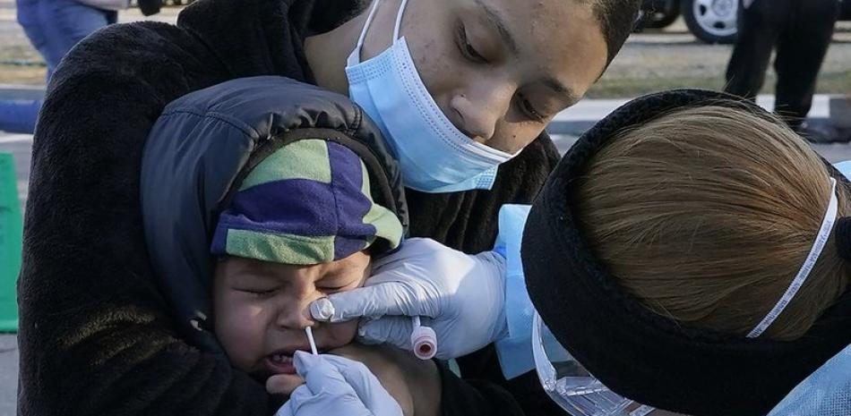Jamillette Gomes sostiene a su hijo Avian, de 2 años mientras le realizan la prueba del coronavirus, en Lawrence, Massachusetts. Foto: AP/Elise Amendola.