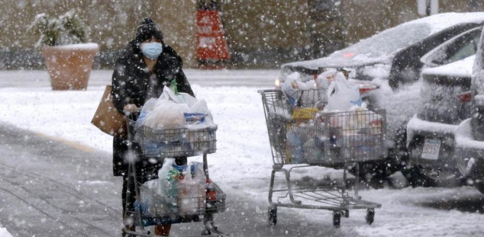 Una persona transporta comestibles en un carrito bajo una fuerte nevada en un estacionamiento en Marlborough, Massachusetts. Foto: AP/Bill Sikes.