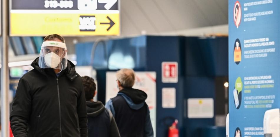 Un pasajero con una mascarilla y un protector facial cruza una terminal el 9 de diciembre de 2020 en el aeropuerto Fiumicino de Roma. Andreas Solaro / AFP