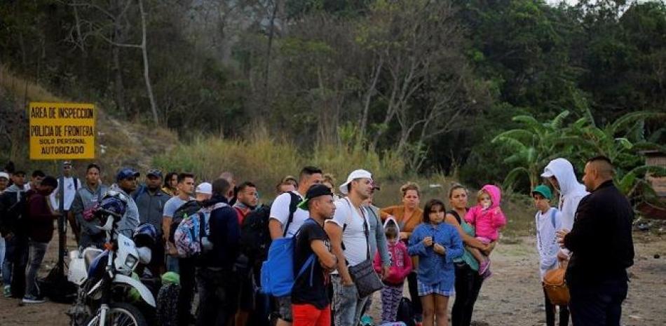 Migrantes cubanos hablan con un agente de migración este viernes al llegar a la Aduana de Agua Caliente (Honduras), fronterizo con Guatemala. En este punto fronterizo se encuentra una caravana migrante convocada por redes sociales y que salió el martes de San Pedro Sula, en el norte hondureño. EFE/ Gustavo Amador