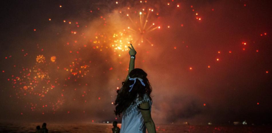In this file picture taken on December 31, 2019 a woman celebrates as she watches the traditional New Year's fireworks at Copacabana Beach in Rio de Janeiro, Brazil. DANIEL RAMALHO / AFP