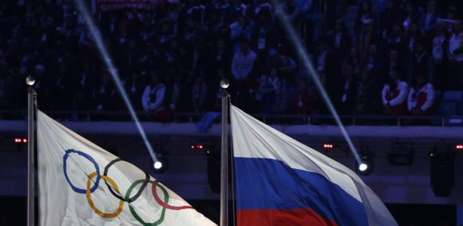 En imagen de archivo del 23 de febrero de 2014, la bandera nacional de Rusia, derecha, ondea al lado de la bandera olímpica durante la ceremonia de clausura de los Juegos Olímpicos de Invierno 2014 en Sochi, Rusia.