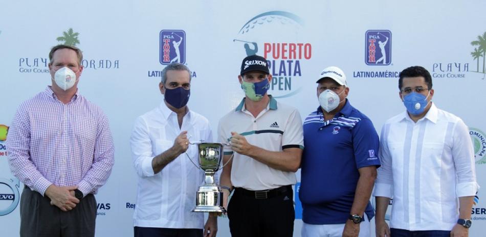 El presidente Luis Abinader entrega la copa al campeón Brandon Matthews. Figuran John Slater, vicepresidente de Competiciones del PGA Tour Latinoamérica; David Collado, ministro de Turismo y Augusto Reyes, presidente Playa Dorada Golf Course.