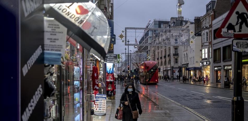 Una mujer camina por una calle húmeda por la lluvia en Oxford el primer día de restricciones de nivel 3 en Londres, el 16 de diciembre de 2020. (Andrew Testa/The New York Times)