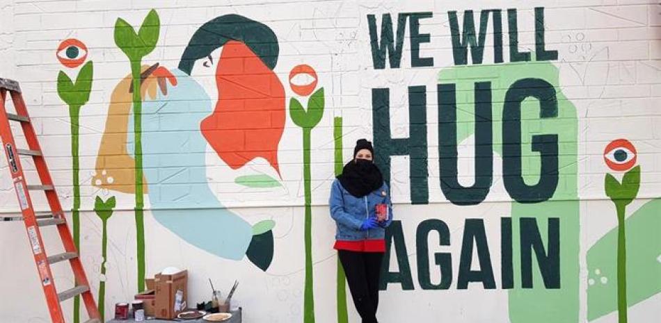 La artista española Vanesa Álvarez trabaja en un mural donde se lee "We will Hug Again" ("Nos abrazaremos de nuevo") que está realizado en la pared de un edificio que está programado su derribo para el próximo marzo, el 23 de diciembre de 2020 en el barrio de Brooklyn en Nueva York (EE.UU.). JORGE FUENTELSAZ