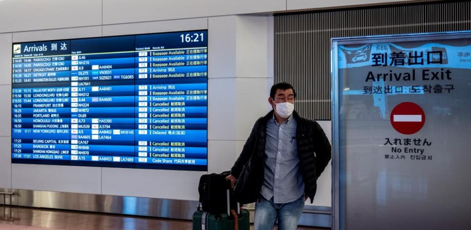Un viajero sale del área de llegadas del aeropuerto de Haneda en Tokio el 27 de diciembre de 2020, luego de que el gobierno anunciara más restricciones de viaje debido al aumento de las infecciones por coronavirus COVID-19 en todo el país.