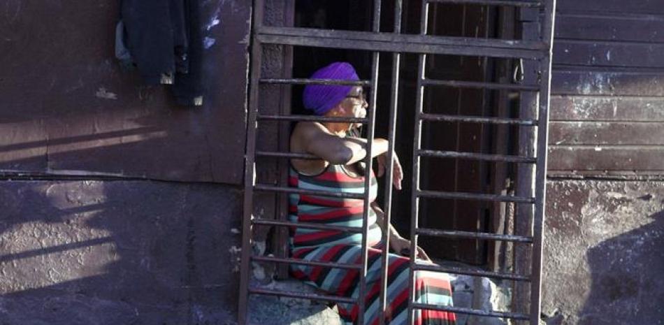 Una mujer luce pensativa sentada en la escalinata de la puerta de su casa, ubicada en la calle Ravelo del sector San Carlos de la capital, en la víspera del final de un año doloroso para los dominicanos, debido al impacto del Covid-19 en la salud y la economía a escala mundial.