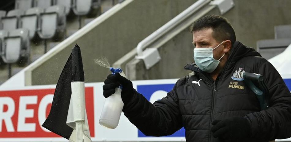Un empleado rocía desinfectante la bandera de córner previo al partido de la Liga Premier inglesa entre Newcastle y Leicester City en el estadio St. James' Park en Newcastle, el domingo 3 de enero. de 2021