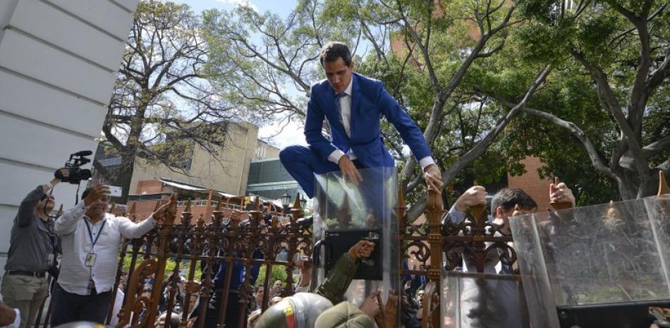 Juan Guaidó, presidente de la Asamblea Nacional saliente de Venezuela y líder opositor, trepa la cerca en un intento fallido para ingresar al complejo de la legislatura. Foto: AP/Matías Delacroix.