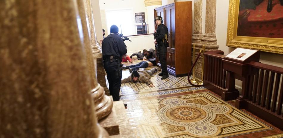 Agentes de la policía del Capitolio retienen a punta de pistola a unos manifestantes cerca del recinto de la Cámara de Representantes, en el Capitolio, en Washington, el miércoles 6 de enero de 2021.

Foto: AP/Andrew Harnik