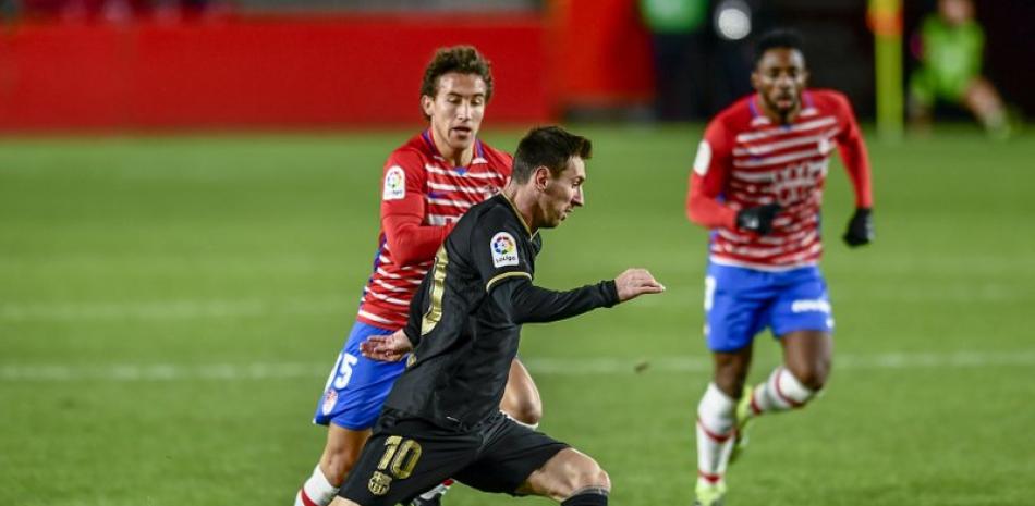 Lionel Messi, del Barcelona, disputa el balón con Luis Milla del Granada en partido por La Liga española en el estadio Los Cármenes, Granada, España, sábado 9 de enero de 2021.