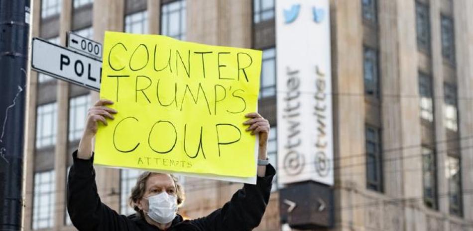 El manifestante Kenneth Lundgreen sostiene un cartel pidiendo la destitución del presidente de los Estados Unidos, Donald Trump, mientras la policía armaba barricadas frente a la sede corporativa de Twitter en San Francisco, California, el 11 de enero de 2021. JOSH EDELSON / AFP